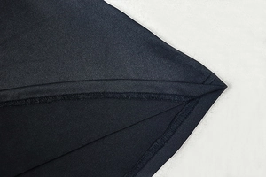 Detail of professional stitching and smooth black synthetic fabric on a bodycon dress