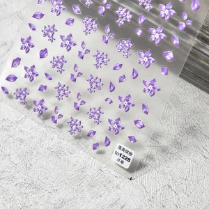 Macro detail of 3D relief flower nail stickers in pearlescent purple floral patterns