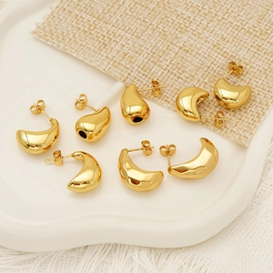 Boucles d'oreilles dorées en forme de goutte et croissant sur plateau céramique