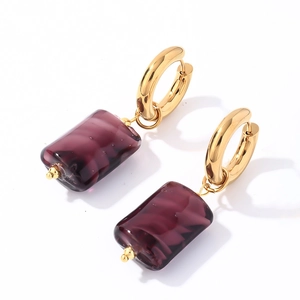 Detail of gold hoops with translucent purple stone pendants showing texture and polish