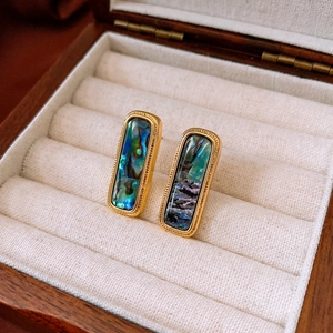 Macro shot of rectangular gold earrings with iridescent shell inlay in a velvet box