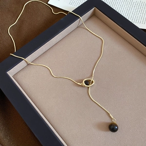 Close-up of golden snake chain with tiger eye shell round pendant in Maillard vintage style