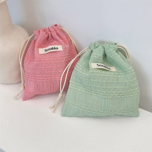 Detail of pink and mint green seersucker drawstring storage bags with textured fabric