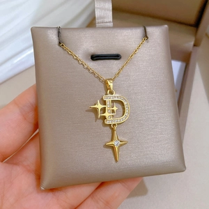 Detailed view of a gold D-letter and star pendant with sparkling pavé zircons