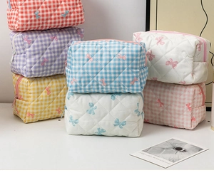 Macro shot of colorful quilted gingham makeup bags with delicate bow embroidery detail