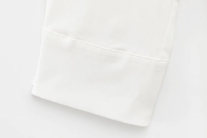 Detailed close-up of white woven fabric with neat stitching on hem or sleeve cuff