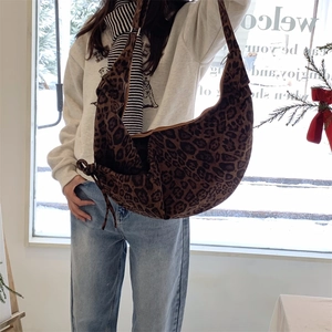Detailed view of leopard print crescent bag on shoulder highlighting the soft suede texture