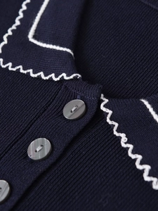 Close-up of navy knit POLO shirt with white wavy stitching and glossy grey buttons