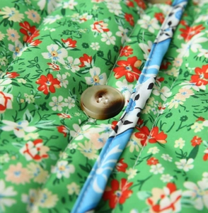 Close-up of quilted floral cotton jacket with green print and marbled resin button detail