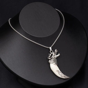 Detailed view of wolf tooth pendant with ornate silver dragon carving and metal chain