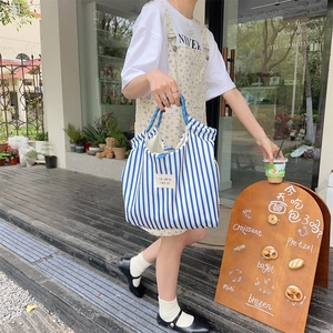 Detail of blue and white striped canvas tote bag with sturdy handles in an outdoor setting