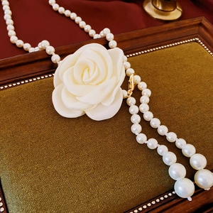 Détail macro du collier rétro français avec perles blanches et grand charm rose en tissu