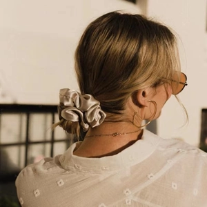Detailansicht eines champagnerfarbenen Satin-Scrunchie an einem tiefen Dutt gestylt