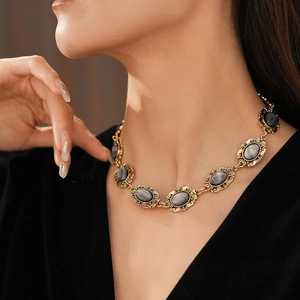 Close-up of vintage golden necklace with oval grey resin gemstones on a model's neck