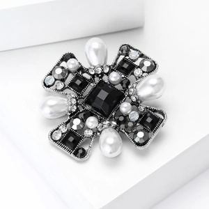 Close-up of Baroque silver brooch with black gemstone, white pearls and sparkling rhinestones
