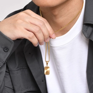 Macro detail of men's golden stainless steel pendant necklace with sunburst engraving