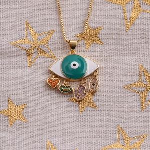 Golden Evil Eye necklace with zircon heart and Hamsa charms on starry beige background