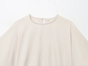 Detail of round neckline and back button closure on beige puff sleeve top, size M
