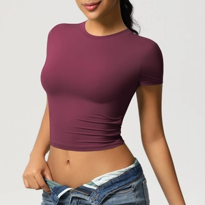 Tight burgundy crop top for yoga and fitness paired with jeans in a studio shot