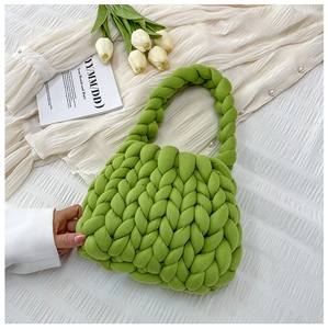 Top view of a soft chunky knit green handbag with white tulips and a notebook