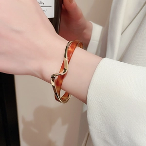 Detailed view of wavy gold-plated metal and amber resin layered cuff bracelet