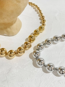 Detailed view of graduated gold and silver beaded necklaces on a beige jewelry bust display