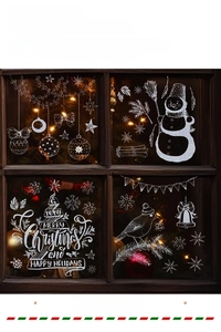 Close-up of white Christmas window stickers with snowman, bells, and stars on glass