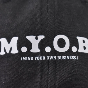 Close-up of black cotton washed baseball cap featuring white M.Y.O.B letter print detail
