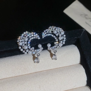 Detail showing crescent moon silver earrings with zircons and drop-shaped pearl pendants