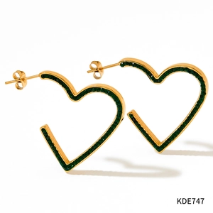 Gros plan de boucles d'oreilles cœur dorées serties de cristaux vert foncé et fermoir
