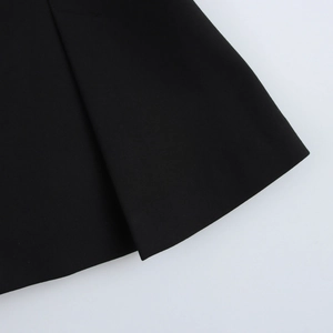 Close-up of black sleeveless vest with pleated hem detail and high-quality fabric texture