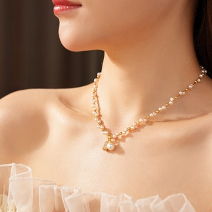 Detail of pearl necklace with gold heart and gourd zircon pendant worn by model