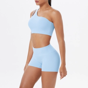 Detail of light blue one-shoulder sports bra and high-waisted shorts set on model