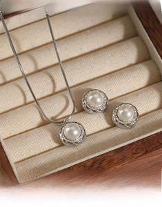 Detail of round pearl jewelry set with hollow grid metal base in a premium display box
