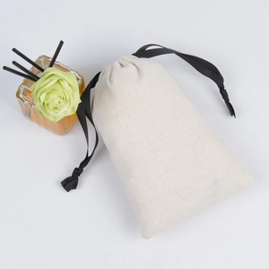 Detail of beige cotton linen jewelry pouch with black drawstring and decorative glass bottle