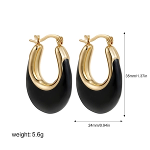 Macro shot of U-shaped enamel hoop earrings with gold and black color-blocking design