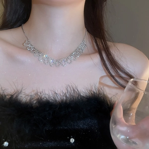Close-up of sparkling rhinestone bow necklace worn by a model in soft focused light