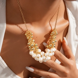 Detail of baroque gold necklace with layered faux pearls and golden beads on model