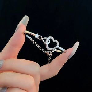 Detail of silver heart infinity bracelet with sparkling zircons on a model's wrist