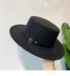 Detailed texture of black wool felt flat top hat with a leather buckle strap decoration