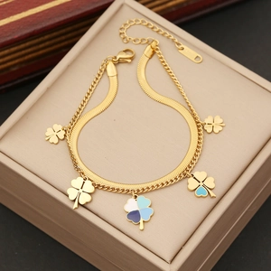 Double-layer gold flower necklace with four-leaf clover charms on a jewelry cushion