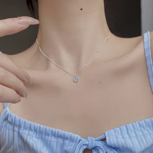 Detailed view of S925 silver heart necklace with rainbow stone on a female model neck