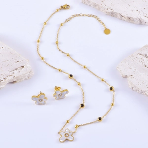Elegant gold flower necklace and stud earrings set with pearl accents on white background