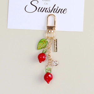 Detail of red persimmon keychain with green leaf and gold clasp for bags
