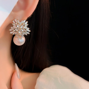 Close-up of elegant gold flower earrings with pearls and crystals worn by a model