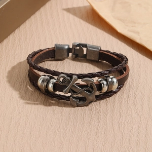 Detail view of brown leather layered bracelet featuring a vintage metal anchor pendant