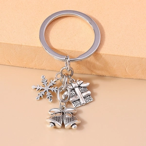 Close-up of silver Christmas keychain featuring snowflake, gift box, and bell charms