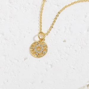 Detailed close-up of a gold-plated necklace with a zircon star pendant on a stone surface
