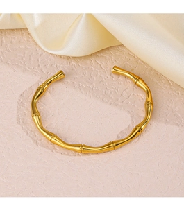 Dettaglio ravvicinato di un bracciale aperto dorato 18K con trama a bambù su seta