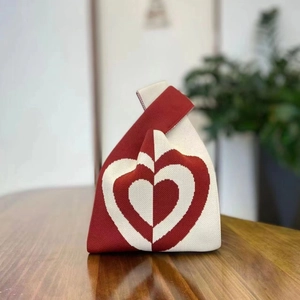 Red and white knitted knot bag featuring a heart pattern and soft fabric texture